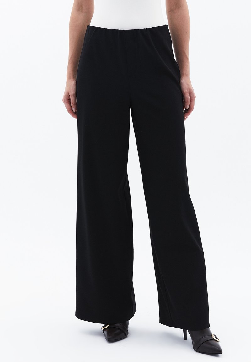 Pantaloni neri a gamba larga con vita elasticizzata, realizzati in un tessuto liscio, con una vestibilità sartoriale e lunghezza completa.