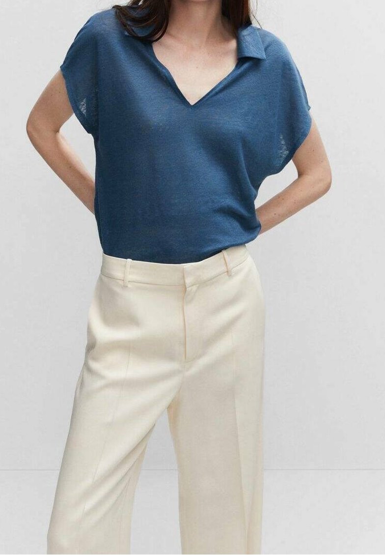 Modrý lehký pletený polo top s výstřihem do V a krátkými rukávy, v kombinaci s krémovými kalhotami na míru se rovný střihem a jemným záhybem.