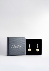 Guldörhängen med ett snäckmönster, uppvisade i en svart smyckesbox med en texturerad utsida och logotyp.