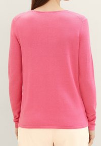 Langärmliger Pullover aus strahlend pinkem Strickstoff. Verfügt über einen runden Ausschnitt, gerippte Bündchen und eine glatte Textur. Keine auffälligen Muster.