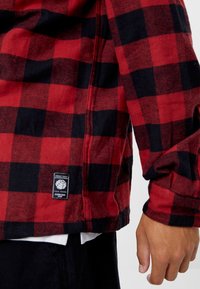 Rood-zwart geruit flanellen overhemd met lange mouwen, voorzien van een label aan de zoom, zachte textuur en een ontspannen pasvorm.