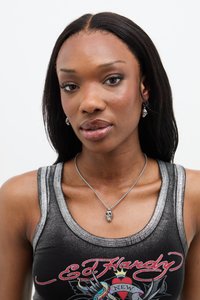 Collana con pendente a forma di teschio in argento su una catena argento, indossata sopra una canotta nera con dettagli metallici e design grafico colorato.