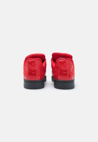 Røde syntetiske sneakers med en blank finish, polstret rød krage og sort gummisåle. Har et præget logo på hælen.