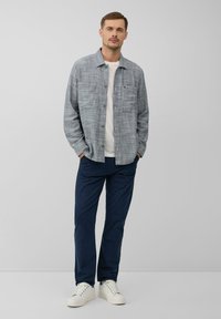 Grijze geblokte button-up shirt van lichtgewicht stof, gecombineerd met marineblauwe broeken en witte sneakers, heeft een borstzak en een relaxte pasvorm.
