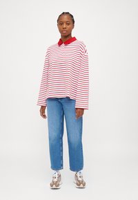 Red and white striped long-sleeve polo shirt with a red collar, paired with light blue straight-leg jeans and beige sneakers.