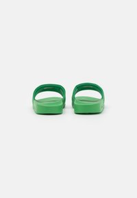 Sandalias de goma verdes con suelas planas y diseño de espalda abierta, que cuentan con correas anchas y una textura suave. Estilo minimalista sin patrones.