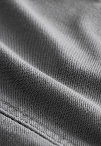 Gray fabric with a fine texture and visible weave pattern, featuring subtle shading. The fabric appears smooth and drapes naturally.