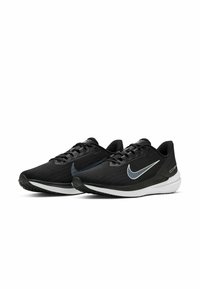 Zapatillas deportivas negras con una parte superior texturizada, media suela blanca y un prominente logo de Nike en plata. Cuentan con cordones y una suela de goma para mayor agarre.