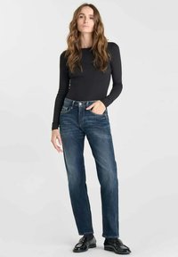 Jeans de mezclilla azul oscuro con un corte recto, combinados con una camiseta ajustada de manga larga negra. Textura suave, detalles de costura sutiles.