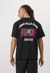 Black cotton t-shirt featuring a graphic print on the back with the text “FINO ALLA FINE,” establishment year "1897," and "JUVENTUS" in white and pink.