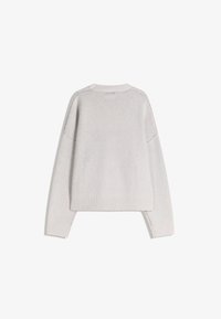 Svetar iz svetlo sive preje s okruglim izrezom, spuštenim ramenima i rebrastim manžetama. Ima ležeran kroj i bočne proreze na rubu.