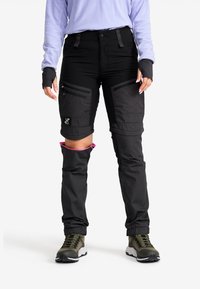 Svarta konvertibla byxor med dragkedjefickor, accentuerade med rosa på den inre fållen, tillverkade av slitstarkt material för utomhusaktiviteter.