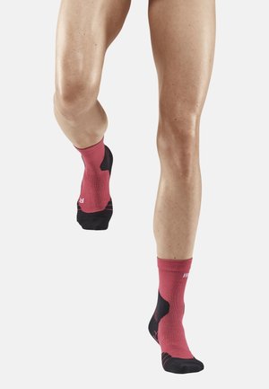 Rote und schwarze Knöchelsocken mit geripptem Muster, gepolstertem Fußbett und verstärktem Zehenbereich. Entwickelt für Komfort und Unterstützung während der Bewegung.