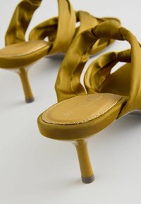 Žluté saténové boty na vysokém podpatku s designem zkrouceného popruhu a hladkým, lesklým povrchem na stiletto podpatku.