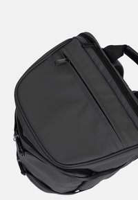 Zaino grigio con un design elegante e arrotondato, materiale testurizzato, numerosi scomparti con cerniera e spallacci regolabili.