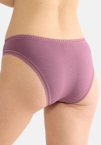 Lila bomullsunderkläder har en slät yta med en dekorativ spetskant längs midjan och benöppningarna, vilket visar upp en klassisk design för briefs.