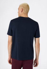 Camiseta de manga corta azul marino hecha de algodón suave, con un cuello redondo clásico y un corte holgado, con una vista trasera lisa.