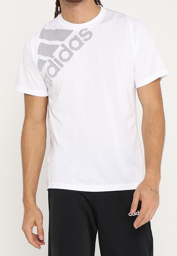 Camiseta deportiva blanca de manga corta con cuello redondo. Cuenta con el logo de Adidas en gris y un gráfico en el lado izquierdo. Acabado de tejido suave.