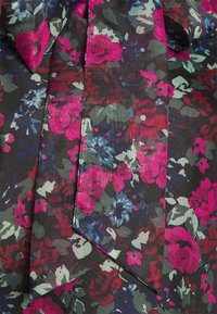 Tessuto floreale con uno sfondo scuro e vivaci fiori rosa, blu e verdi. Include una cravatta e una finitura texturizzata.