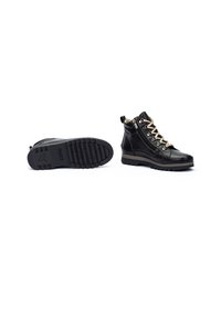 Bottines en cuir noir avec une semelle en caoutchouc texturé, bout arrondi et œillets en ton doré. Elles sont dotées de lacets décoratifs et d'une languette.