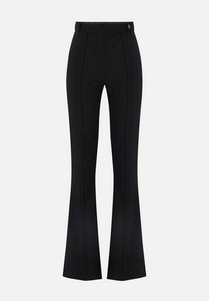 Pantaloni neri su misura a vita alta con cuciture frontali e gambe svasate, caratterizzati da un piccolo emblema metallico vicino alla cintura.