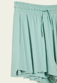 Lichtmintgroene korte broek met een elastische tailleband en trekkoord. Heeft een gelaagd ontwerp met zachte, gladde stof en subtiele plooien.