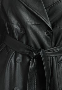 Abrigo largo de cuero negro con cintura con cinturón, cierre de botones doble, y textura suave, que muestra costuras detalladas y solapas.