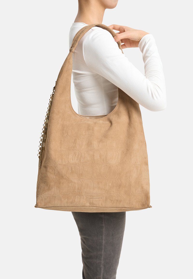 Beige Kunstwildleder-Umhängetasche mit strukturierter Oberfläche, weiter Schlitzöffnung und goldfarbenem Kettendetail auf einer Seite.