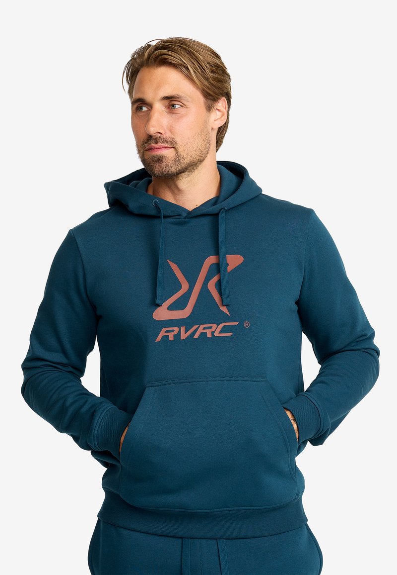 Turchinsydd hoodie iverkledt i mjukt materiale med kengurulomme og stor RVRC-logo i rustfarge foran. Klassisk passform med snor i hetten.