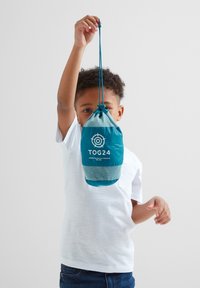 Teal lightweight drawstring bag with mesh section, featuring "TOG24" logo. Held by a child, displaying its compact, portable design.