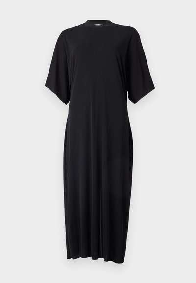 Robe noire à manches courtes en tissu doux, présentant une silhouette droite et un col montant avec des fentes sur les côtés pour faciliter les mouvements.