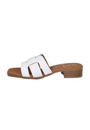 Sandalia blanca de punta abierta con tres tiras anchas, plantilla acolchada marrón y tacón bajo apilado sobre fondo blanco.