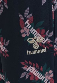 Donkere stof met een bloemenpatroon in roze en groen, met het witte geborduurde "hummel" logo en aanvullende gestreepte bladdesigns.