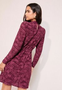 Garais piedurkņu bordo kleita ar ziedu mežģīņu tekstūru, pieguloša jostas vieta un atslēgas cauruma detaļa mugurā. Gluda auduma ar maigu kritumu.