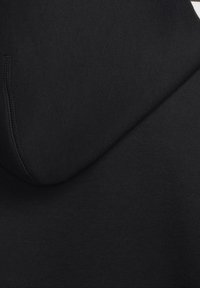 Černá mikina s kapucí z měkkého materiálu, s zaoblenou kapucí a jemnými švy. Tkanina působí hladce a jednotně.