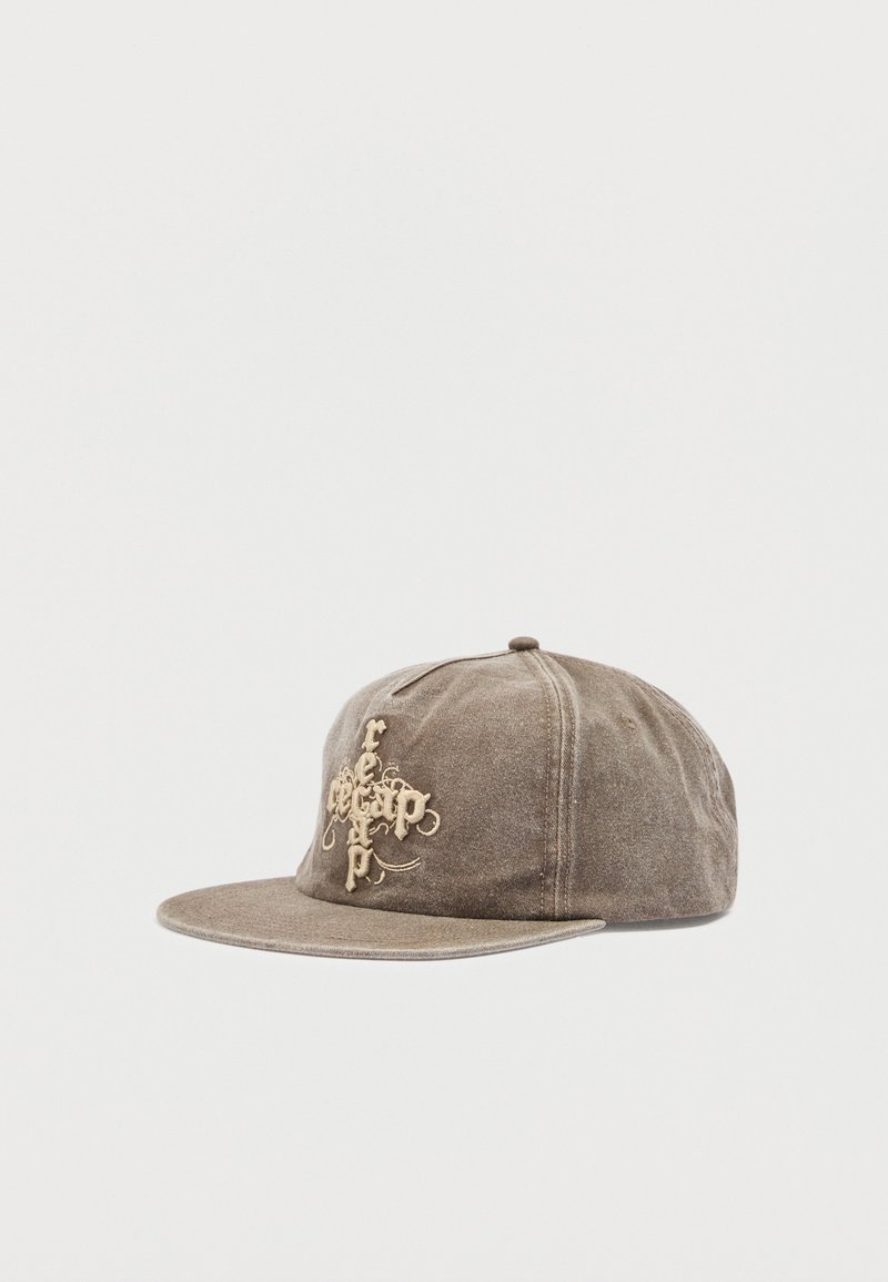 Gorra de béisbol de gamuza marrón con visera plana y bordado en relieve color canela que presenta un texto estilizado en el panel frontal.