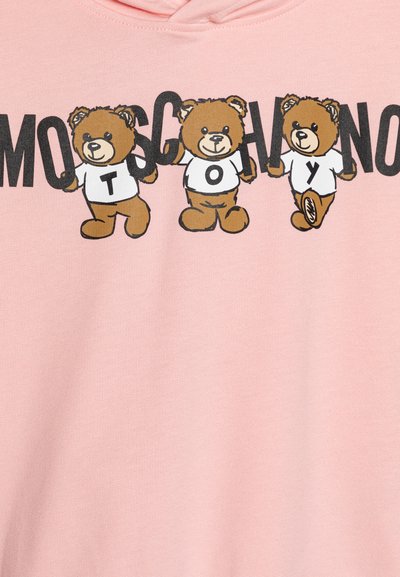 Felpa rosa con tre orsi in cartone animato che indossano magliette bianche, con lettere nere in grassetto che scrivono "MOSCHINO TOY" sopra di loro. Tessuto morbido.