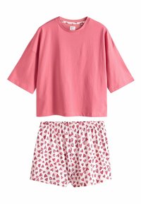 Lyserød bomulds T-shirt med korte ærmer kombineret med hvide shorts med et gentaget mønster af lyserøde hjerter og elastisk talje.