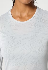 Lekka biała koszula z długim rękawem o gładkiej fakturze, z subtelnymi liniowymi wzorami i klasycznym okrągłym dekoltem.