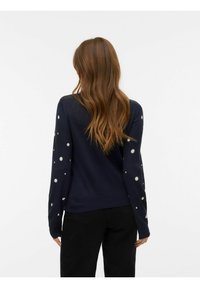 Granatowy sweter z gładkim tyłem i długimi rękawami w białe, okrągłe wzory, wykonany z miękkiego, lekkiego materiału.