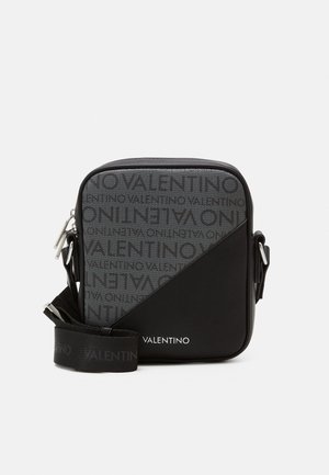 Black crossbody bag with textured gray logo pattern, triangular design, and adjustable strap featuring "Valentino" branding. Zipper closure.