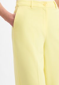 Geele tailleurbroek met een gladde textuur, zijzakken en een knoopsluiting. Heeft een klassieke pasvorm met rechte benen.