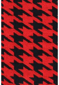 Czerwono-czarny wzór w jodełkę na dzianinie o gładkiej fakturze, z wyraźnie kontrastującymi kształtami w powtarzającym się wzorze.