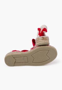 Sandalia espadrille roja y blanca con textura trenzada, detalles de yute y suela de goma. Notables lazos de tela roja en la parte posterior.