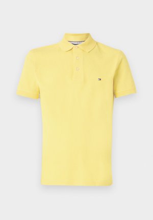 Polo shirt jaune en coton doux, avec un col classique, une patte de boutonnage à trois boutons et un petit logo sur la poitrine.