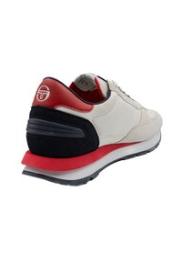 White sneaker with red and navy accents, suede and leather materials, rounded toe, and textured sole. Logo detailed on heel.