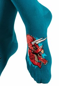 Türkisfarbene Baumwollsocken mit einem roten Dinosaurier-Design, weißen Hörnern, detaillierten Gesichtszügen und bunten Akzenten an den Seiten.