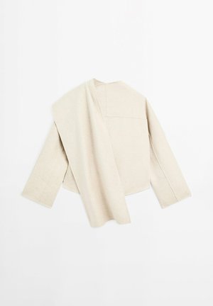 Veste beige texturée avec une coupe ample, dotée d'un seul panneau drapé sur une épaule et de manches larges, avec des coutures minimales et sans fermetures.