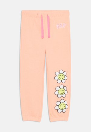 Pantaloni della tuta color pesca chiaro con una vita elastica e lacci rosa. Presentano tre fiori cartoni animati con facce sorridenti stampati sulla gamba sinistra.