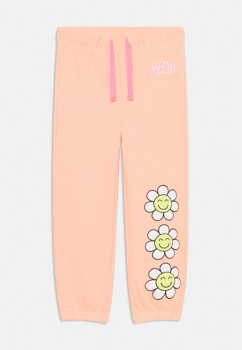 Lyse ferskenfargede joggebukser med elastisk midjebånd og rosa snorer. Har tre tegneserieblomster med smilende ansikter trykket på venstre ben.